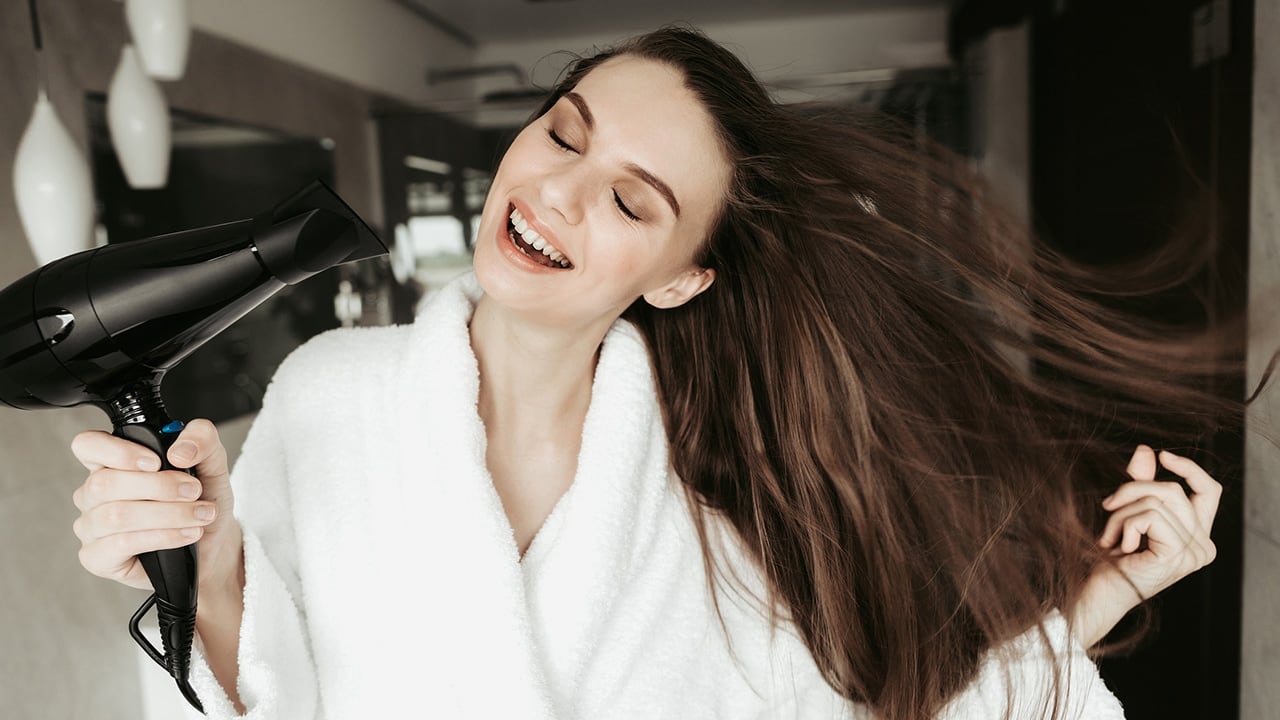 Cabeleireiro seca o cabelo com secador de cabelo para uma mulher