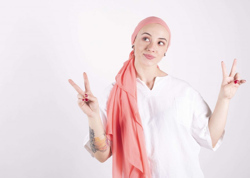 mulher com câncer com lenço rosa sobre a cabeça