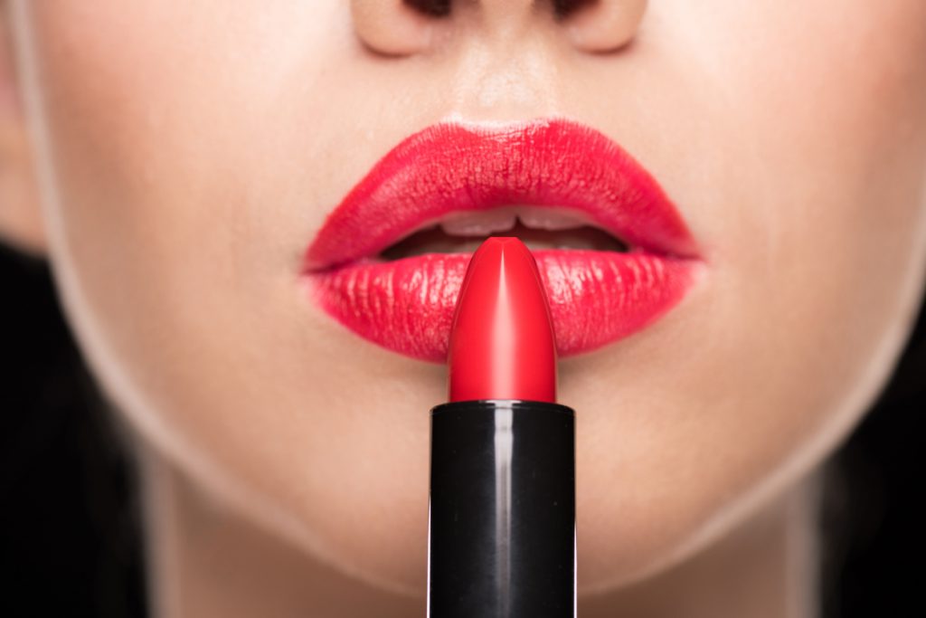 Uma mulher passa batom vermelho nos lábios