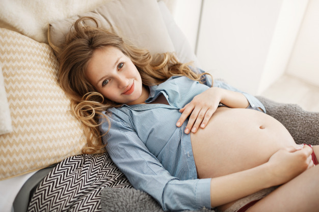 mulher gravida sorrindo com a barriga a mostra