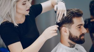 cabelereira cortando o cabelo de cliente homem