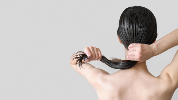 mulher de costas no banho segurando cabelo